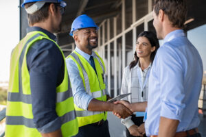 Workers and businessman handshake at construction site